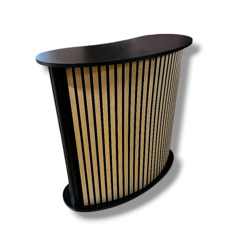 Gebogene Theke mit Ablage. Front mit Akustikpaneel/Holzlamellen. B 104 x T 43 x H 105 cm.