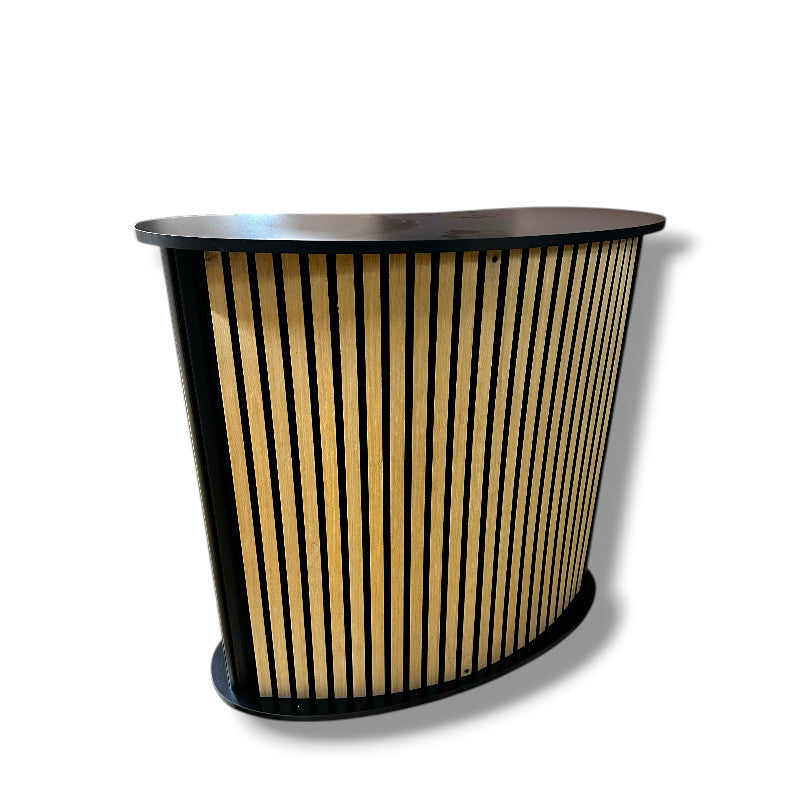 Gebogene Theke mit Ablage. Front mit Akustikpaneel/Holzlamellen. B 104 x T 43 x H 105 cm.