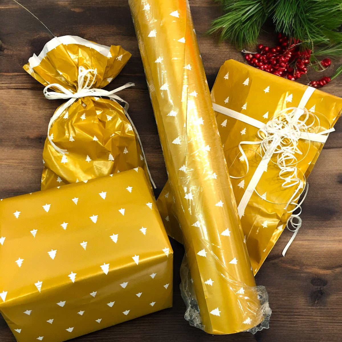 Detalje af julegavepapir med hvide juletræer og guld baggrund